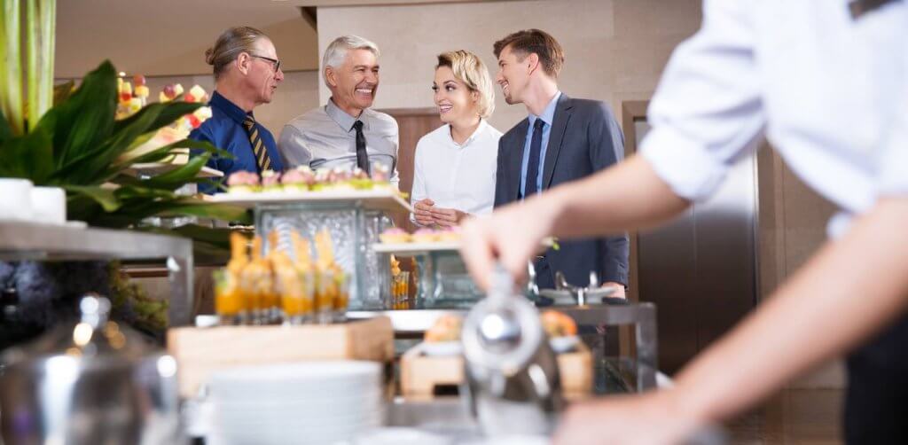 four smiling business people at buffet table